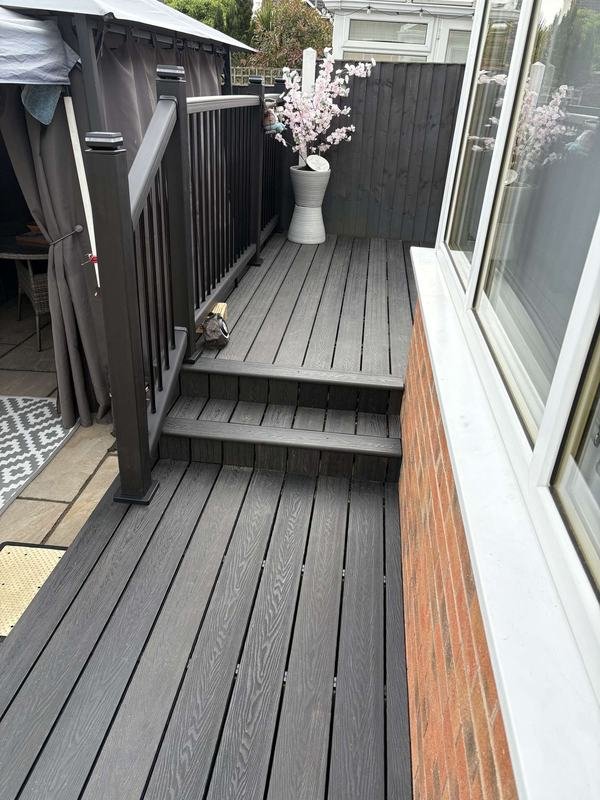 Charcoal composite decking and steps beside a conservatory in Abenbury, Wrexham