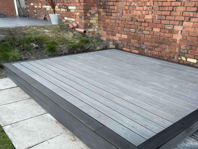Grey composite decking with a charcoal border laid in a Rhosllanerchrugog garden