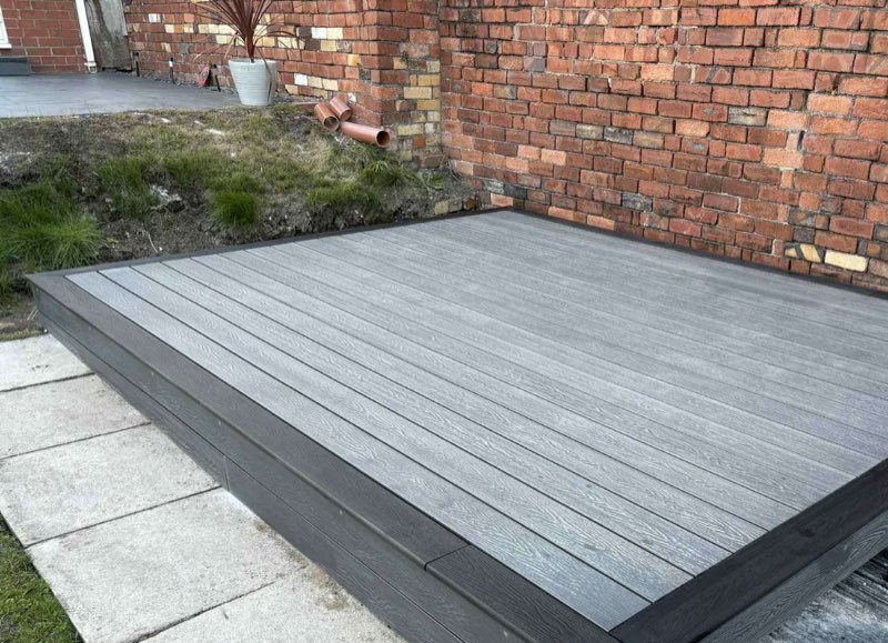 Grey composite decking with a charcoal border laid in a Rhosllanerchrugog garden