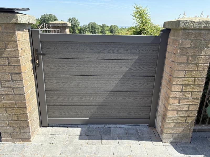 Grey composite gate fitted between brick pillars in Borras, Wrexham