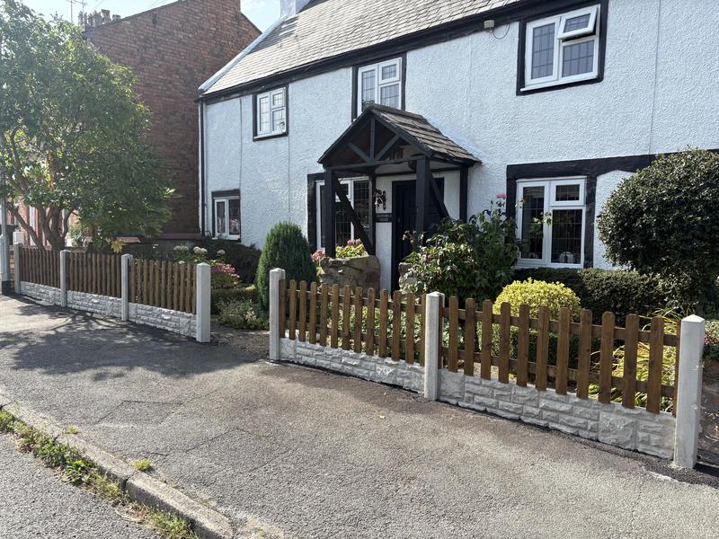 Picket fencing on concrete posts across the front of a cottage in Caegwrle, Wrexham