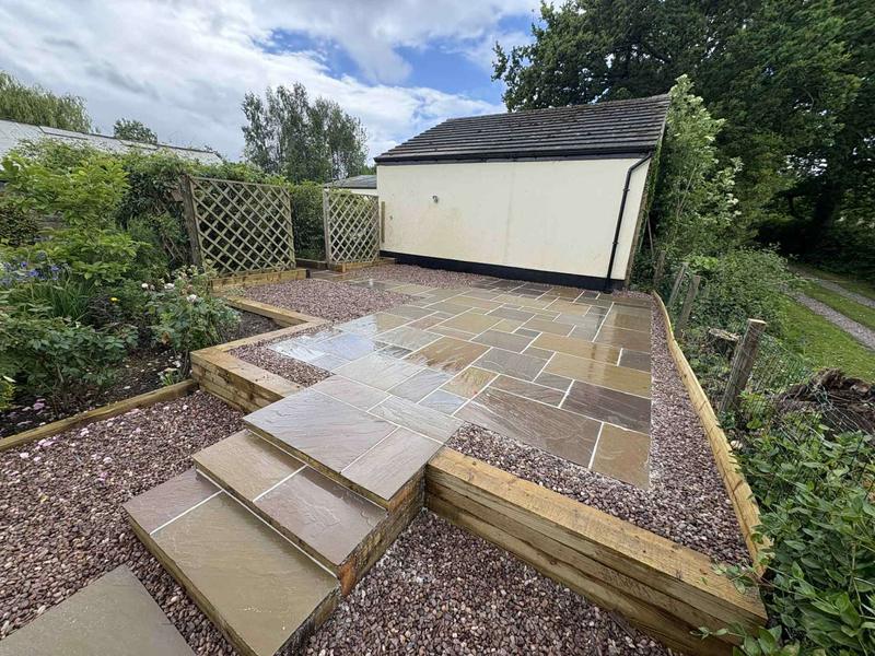 Raj blend Indian sandstone paving with sleeper retaining walls and gravel detail in Rossett, Wrexham