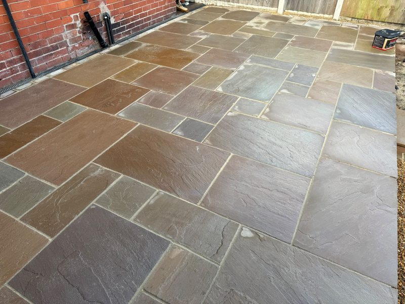Raj Green Indian stone patio laid against the brick wall of a house in Gwersyllt, Wrexham