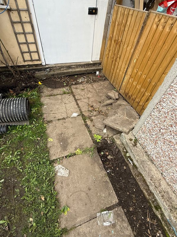 The cracked and crumbling path by the side gate in Gwersyllt with loose paving slabs