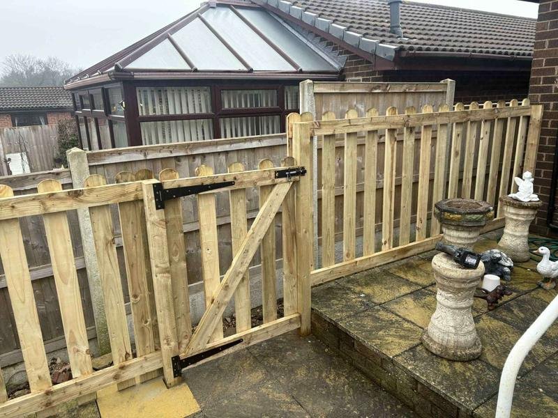 Picket fencing and a sleeper retaining bed alongside a conservatory in Borras, Wrexham