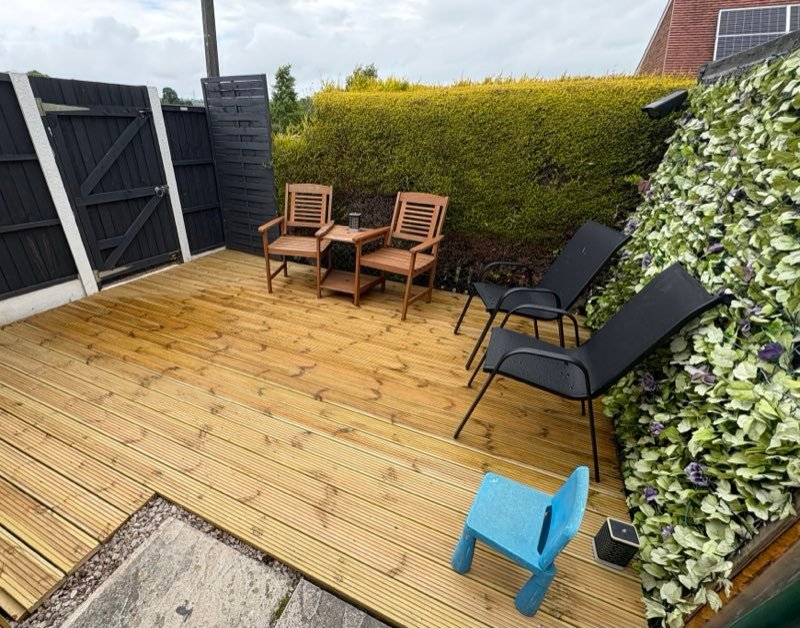 New timber decking with garden furniture beside a hedge in Coedpoeth, Wrexham