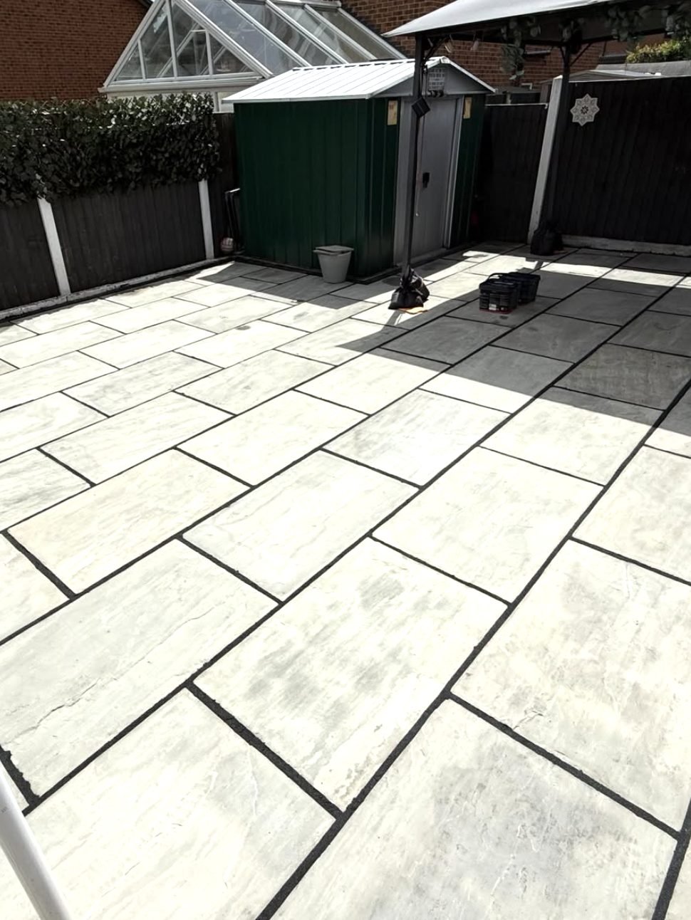 Light grey sandstone patio with contrasting dark pointing laid across a Wrexham garden by SJE Landscaping Solutions